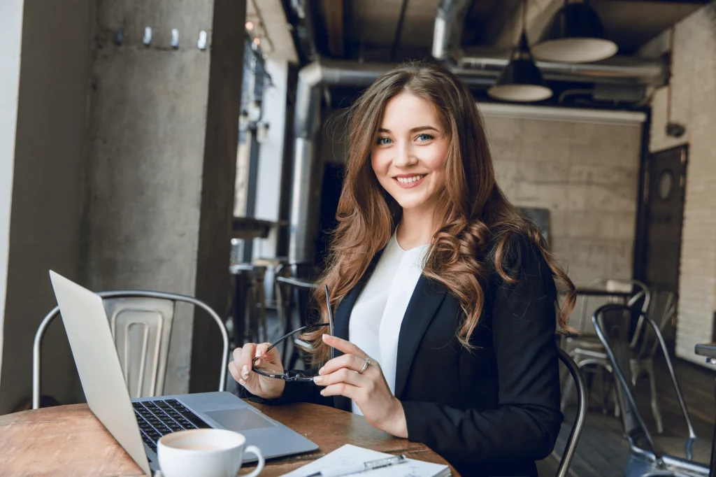 widely-smiling-businesswoman-working-laptop-sitting-cafe